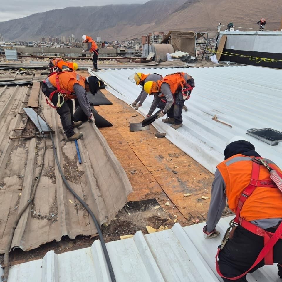 Cuadrilla con arnés retirando cubierta antigua e instalando techumbre nueva en Iquique